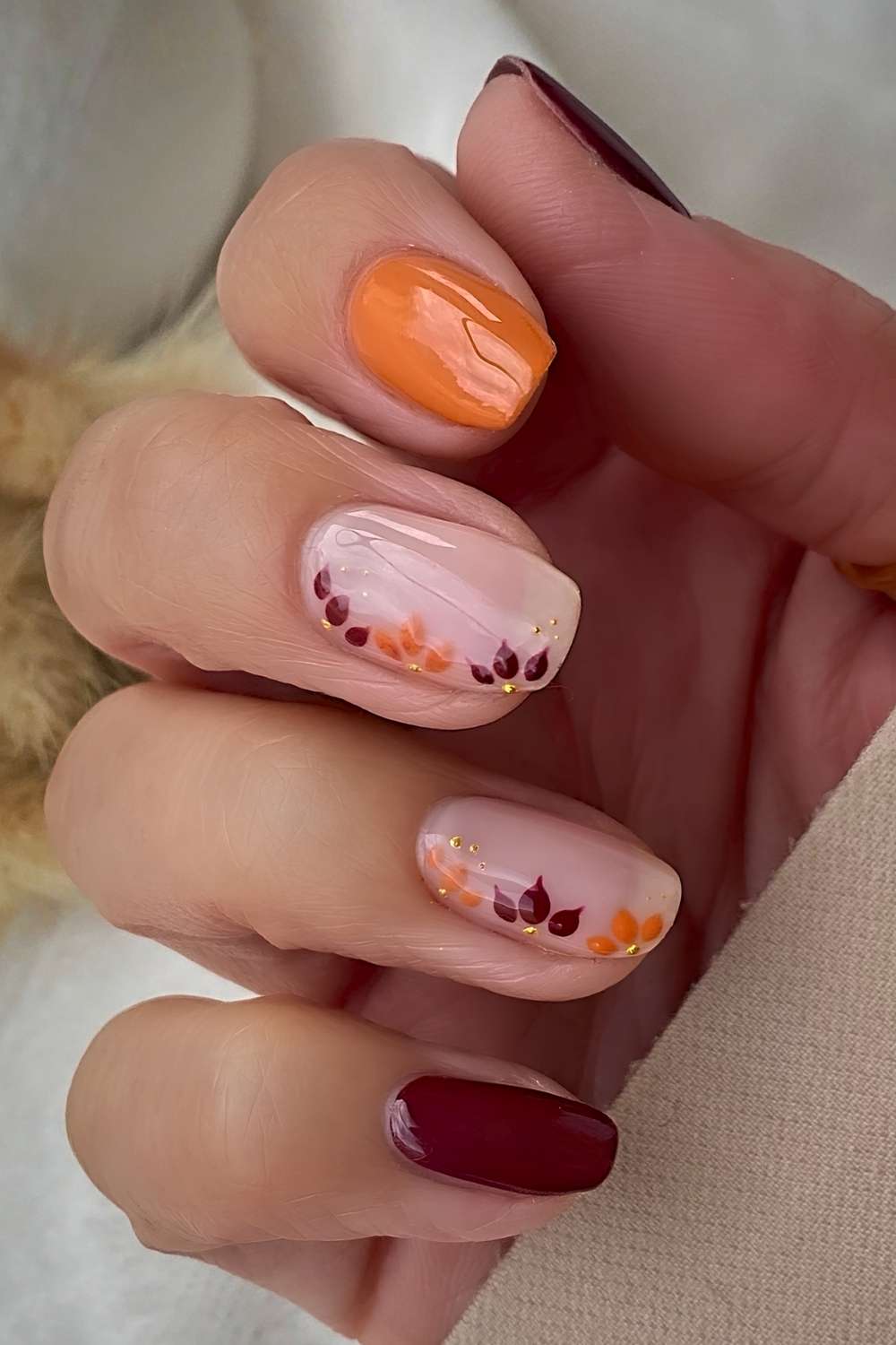 Dunkelrote und kuerbisorange Blumennaegel