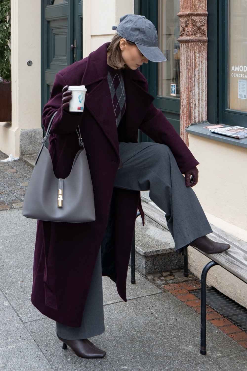 Burgunderroter Mantel mit Rautenpullover und grauer Hose